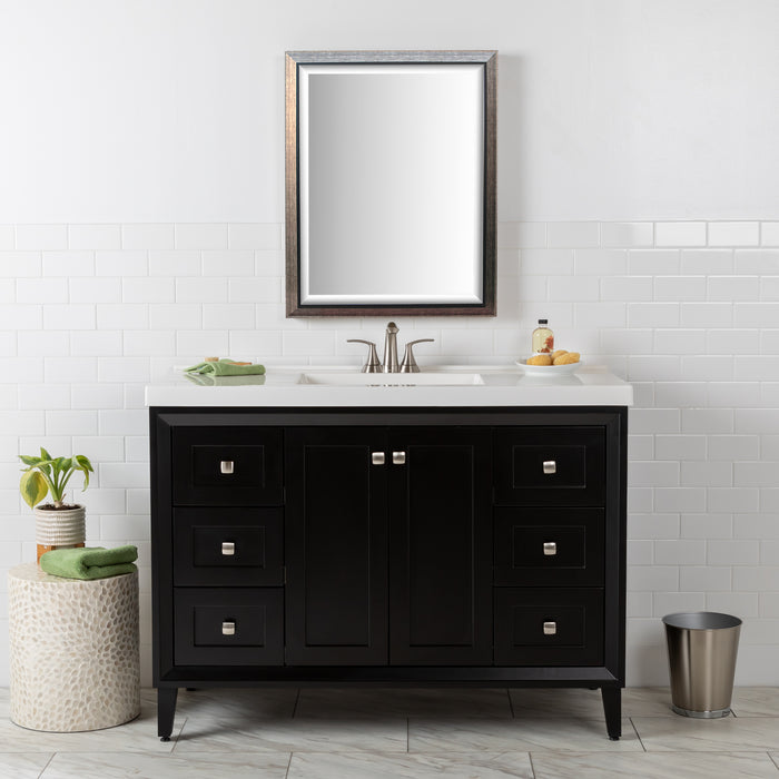 Front view of the Beckett 49" wide furniture-style bathroom vanity with black cabinet finish, white sink top, 2 soft-close doors, 6 drawers, and fine grain nickel pulls. Shown with mirror, soap dish, hand towel and other bathroom items.